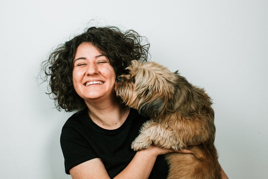 dog kissing woman in black crew-neck shirt