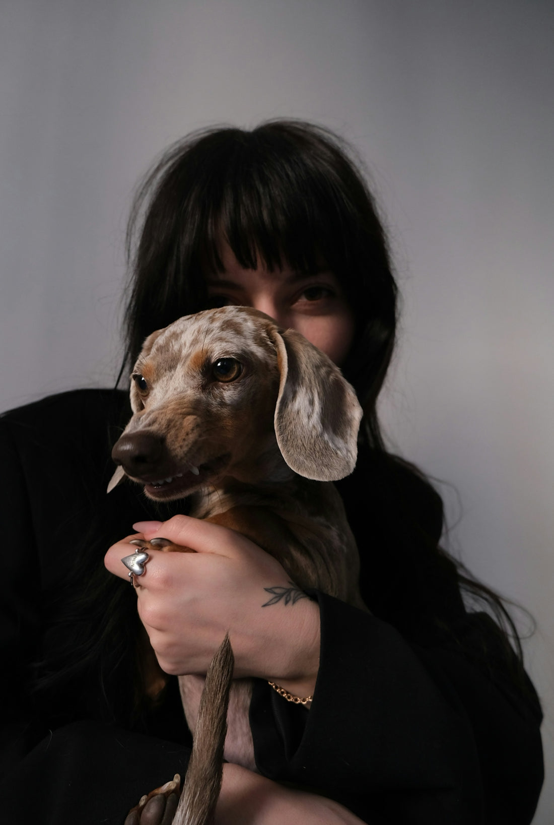 Woman holding a small spotted dachshund dog